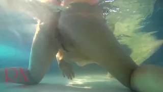 Elegant and flexible babe, swimming underwater in the outdoor swimming pool.