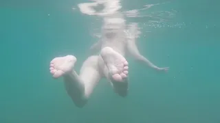 Nudist beach: Skinny dipped girl swimming in the sea.