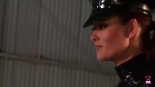 A seductive law enforcement officer clad in a latex costume engages in intimate relations with an attractive woman with ample and aesthetically pleasing bosoms.